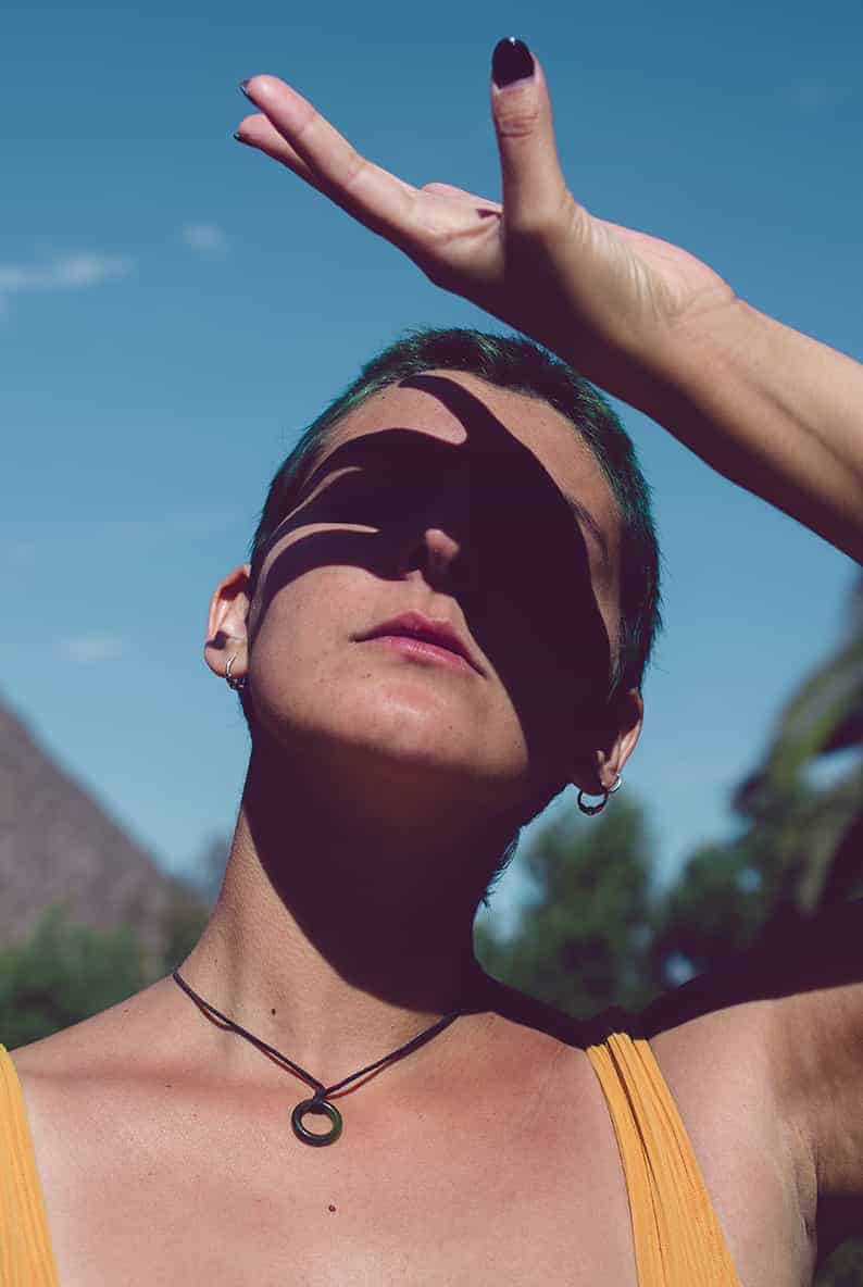 Imagen de una mujer mirando el sol y cubriéndose los ojos